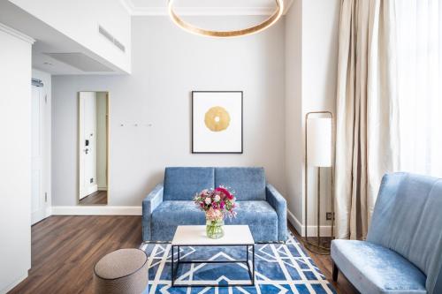 a living room with a blue couch and a table at Fraser Suites Hamburg in Hamburg
