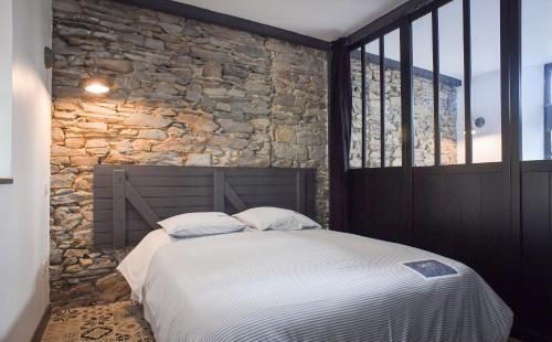 a bed in a room with a stone wall at Domaine de la Palombe in Villiers-Fossard