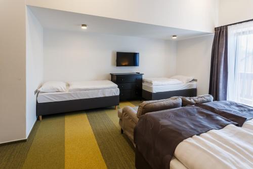 a hotel room with two beds and a tv at Restaurace a penzion Pod Lipami Metylovice in Metylovice