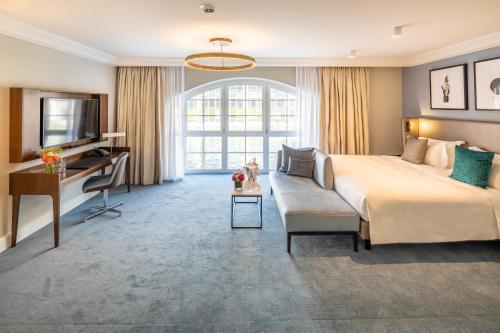 a hotel room with a bed and a couch and a tv at Fraser Suites Hamburg in Hamburg