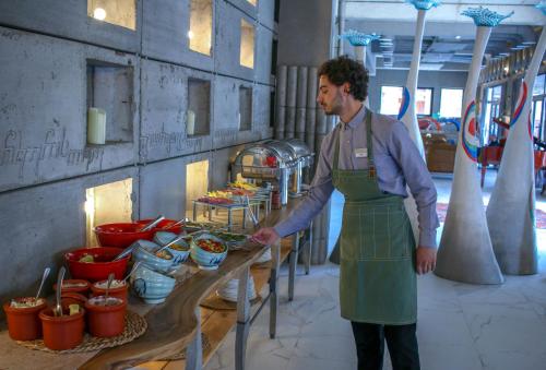 a man wearing a green apron standing in a kitchen at Brim Hotel in Tbilisi City