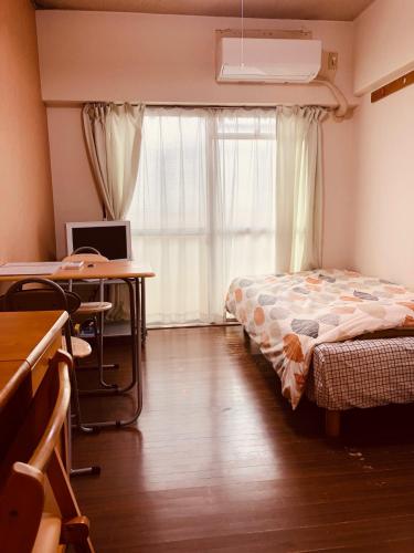 a bedroom with a bed and a desk and a window at Nishijin Ivy in Kyoto
