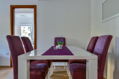a dining room table with purple chairs and a white table at Apartmani Marina Kopitovic in Petrovac na Moru
