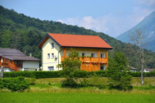 a house with an orange roof in front of a mountain at HišaŠmihelka in Kobarid