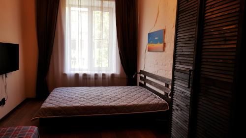 a bed sitting in a room with a window at Апартаменты в центре Новосибирска Урицкого 12 in Novosibirsk