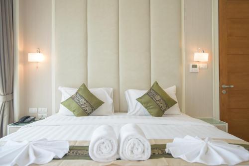 Un dormitorio con una cama blanca con toallas. en GM Serviced Apartment (SHA Certified), en Bangkok