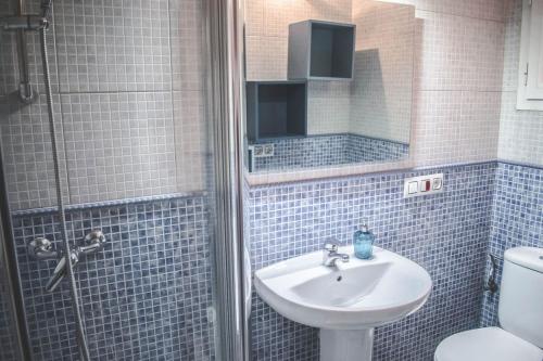 y baño de azulejos azules con lavabo y ducha. en Alojamiento Lirio, Céntrico y cerca de la Playa en Vilanova i la Geltrú