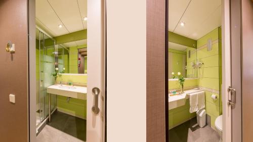 a green bathroom with two sinks and a mirror at Bonanova Suite in Barcelona