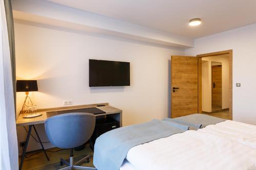 a bedroom with a bed and a desk and a television at Restaurace a penzion Pod Lipami Metylovice in Metylovice