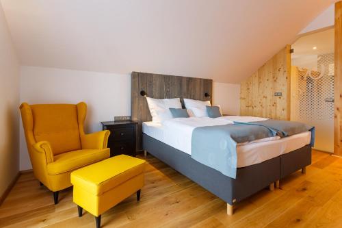 a bedroom with a bed and a yellow chair at Restaurace a penzion Pod Lipami Metylovice in Metylovice