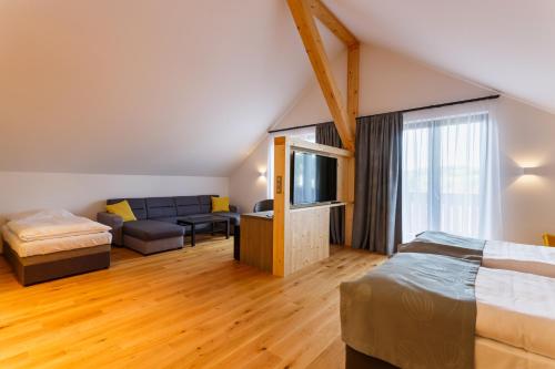 a room with a bed and a couch and a tv at Restaurace a penzion Pod Lipami Metylovice in Metylovice