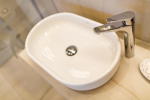 a white bathroom sink with a faucet on a counter at Restaurace a penzion Pod Lipami Metylovice in Metylovice