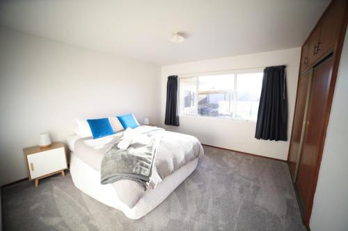a white bedroom with a bed and a window at Rejuvenate on Rata FREE WIFI in Twizel