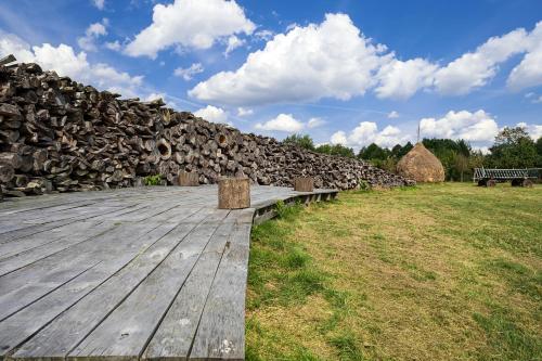 a wooden deck with a bench and a pile of logs at Spreewaldresort Seinerzeit in Schlepzig