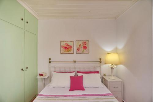 Un dormitorio con una cama con almohadas rosas y blancas. en Spring Bliss Garden House, en Skopelos Town