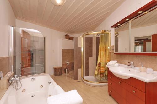 Un baño con bañera, lavabo y ducha. en Spring Bliss Garden House, en Skopelos Town