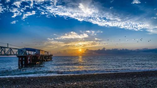 a pier on the beach with the sunset in the background at ALEX'S HOUSE in K'obulet'i