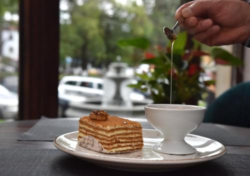 a person eating a piece of cake and a cup of coffee at LETO Boutique Hotel Zugdidi in Zugdidi
