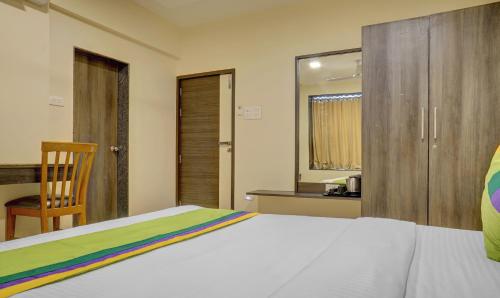 a bedroom with a bed and a chair and a window at Treebo Bhagyashree Executive in Pune