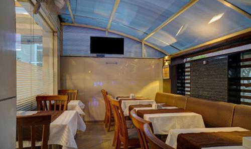 a dining room with tables and a tv on the wall at Treebo Bhagyashree Executive in Pune
