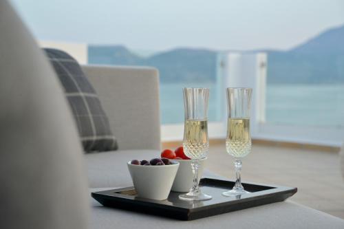 two wine glasses and a bowl of fruit on a tray at Ostria Hotel  in Adamas
