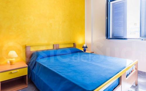 ein Schlafzimmer mit einem blauen Bett und einer gelben Wand in der Unterkunft Appartamento Da Maria in Torre Vado