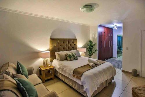 a bedroom with a large bed and a couch at Komorebi Ballito in Ballito