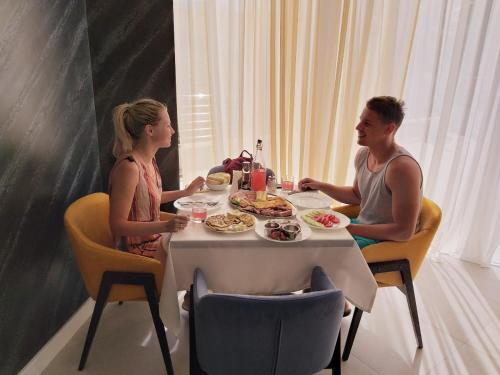 Un hombre y una mujer sentados en una mesa comiendo comida en Hotel Pierina, en Budva