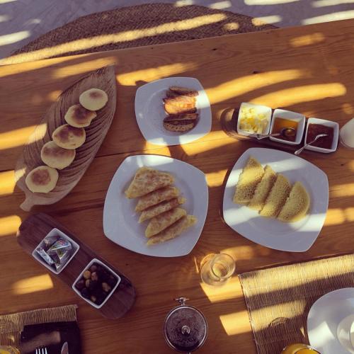 马拉喀什PALAIS SOHAN的一张木桌，上面摆放着食物盘子