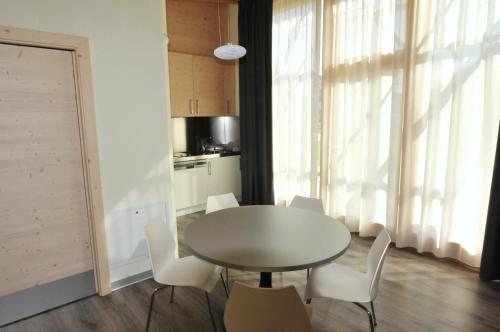 a dining room with a table and white chairs at Bungalows Chalets Lago di Molveno in Molveno