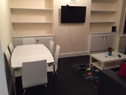 ein Wohnzimmer mit einem weißen Tisch und einem TV in der Unterkunft Marble Apartments Tooting House in London