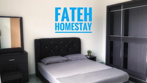 a bedroom with a bed with a black headboard and a mirror at Fateh Homestay in Arau
