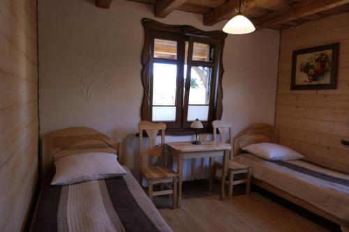 a room with two beds and a table and a window at Dom Gościnny BIERWIONO in Cisna