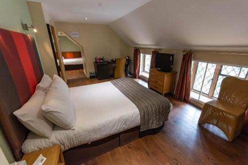 1 dormitorio con 1 cama, TV y silla en Great Hallingbury Manor en Bishops Stortford