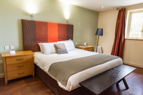 a bedroom with a large bed with an orange headboard at Great Hallingbury Manor & Lodges London Stansted in Bishops Stortford