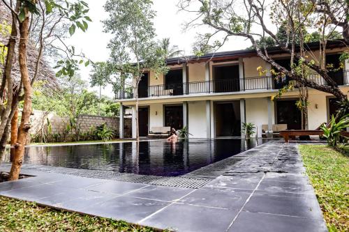 una persona che nuota in una piscina di fronte a una casa di il Frangipane a Sigiriya