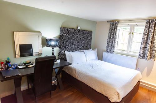 a hotel room with a bed and a desk with a computer at Great Hallingbury Manor & Lodges London Stansted in Bishops Stortford