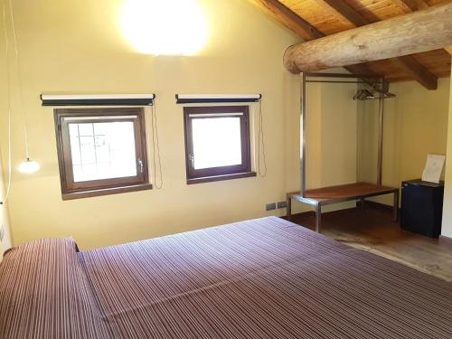 a bedroom with a bed and two windows and a table at Villa Ottocento in Campertogno