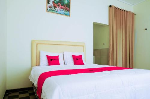 1 dormitorio con 1 cama blanca grande con almohadas rojas en RedDoorz near STAB Syailendra Kopeng, en Salatiga