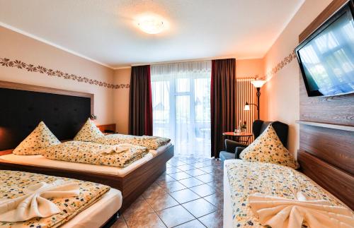 a hotel room with two beds and a flat screen tv at Hotel-Restaurant zum Ochsen in Schallstadt
