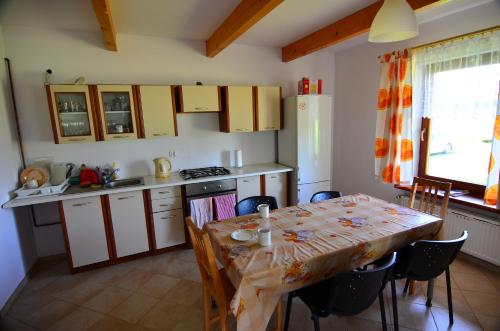 a kitchen with a table and chairs and a kitchen with a table and a table at Białowieska Chata in Białowieża