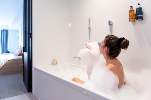 a woman sitting in a bath tub with a stuffed animal at Hotel Nelson in Knokke-Heist