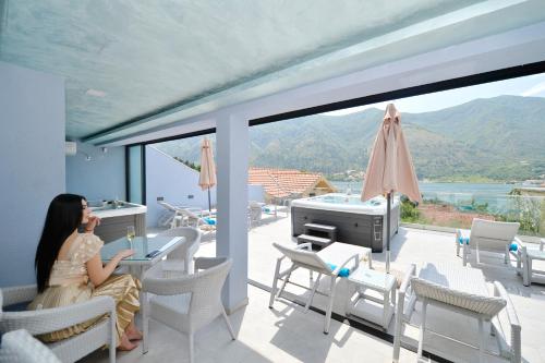a woman sitting at a table on the balcony of a house at Apartments Jovanovic - Alkima in Kotor
