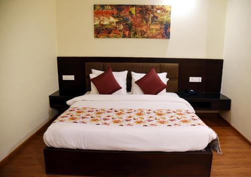 a bedroom with a large bed with red pillows at Clarks Inn Suites Katra in Katra