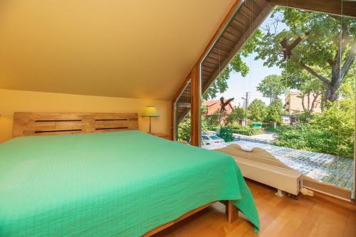 een slaapkamer met een bed en een groot raam bij Vila PRI Rouzes in Palanga