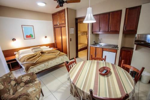 a room with a bed and a table and a kitchen at Residencial Pousada Serrano in Gramado
