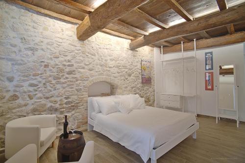 1 dormitorio con cama blanca y pared de piedra en La Ruetta in pieno centro storico, en Ascoli Piceno