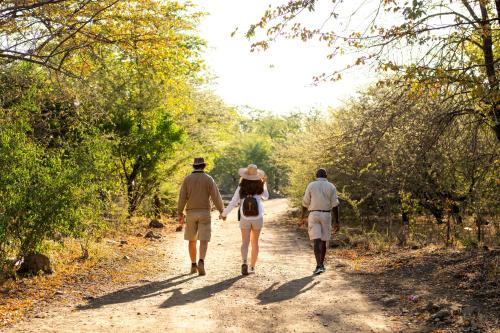a group of three people walking down a dirt road at Ichingo Chobe River Lodge by Mantis in Punga