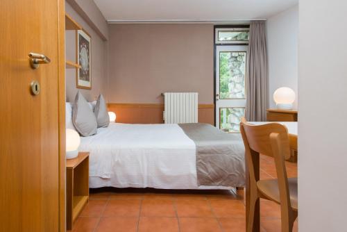 1 dormitorio con cama blanca y ventana en Appartamenti Corte Residence en Borca di Cadore