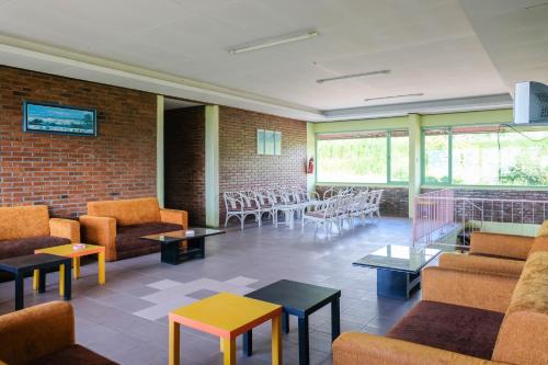 a waiting room with couches and tables and chairs at RedDoorz Syariah near Kopeng Treetop Adventure in Salatiga